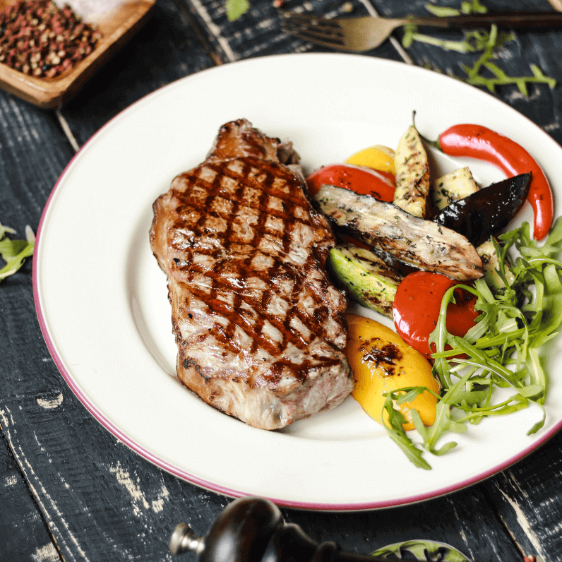 A white plate with a grilled steak and roast vegetables.