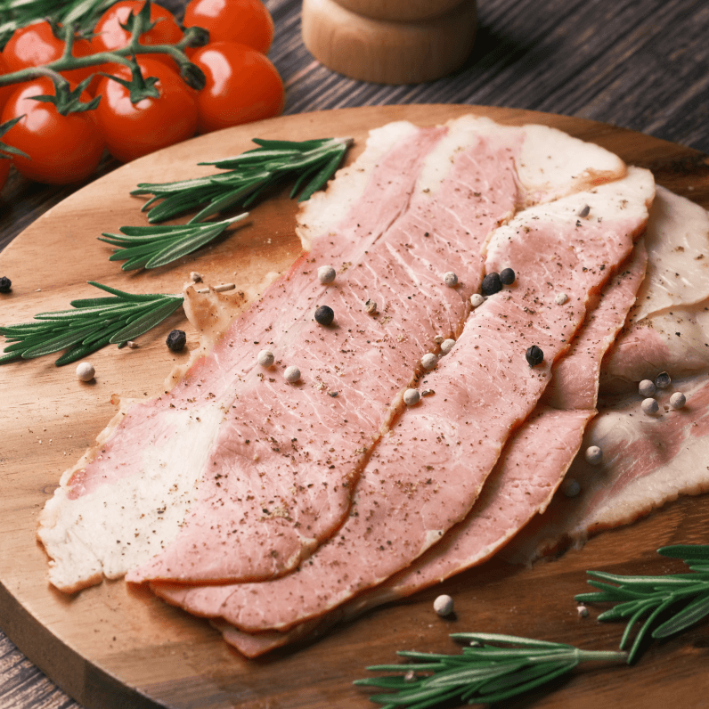 A chopping block with pieces of cooked bacon.