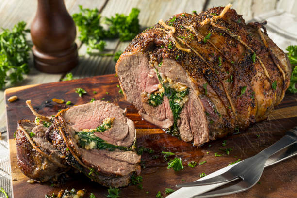A chopping board with a joint of roast lamb on it.