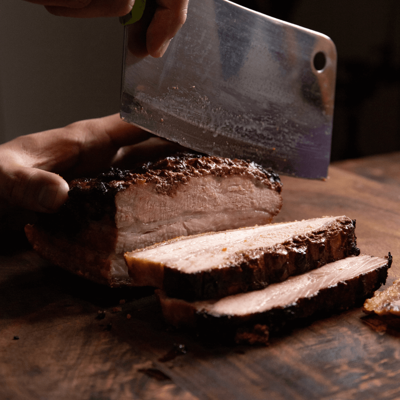 A man hand carving a joint of roast pork.